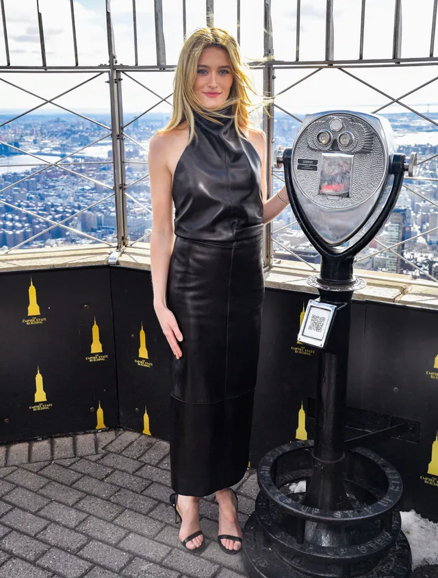 Sarah Pidgeon wearing a black top, skirt and heels at an observation deck.