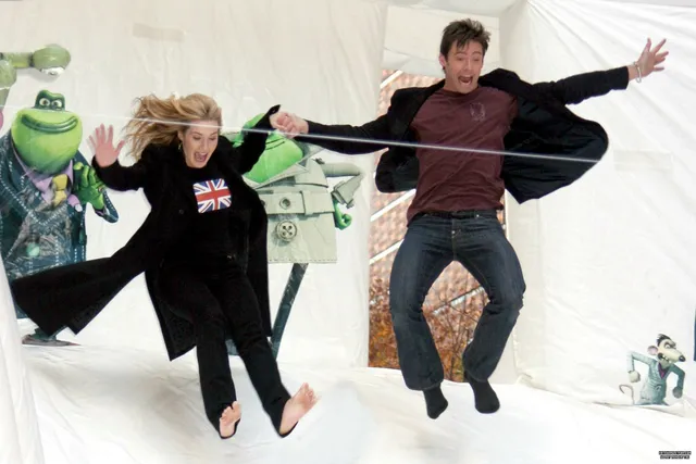 Kate Winslet reclining barefoot beside a companion on a white background.