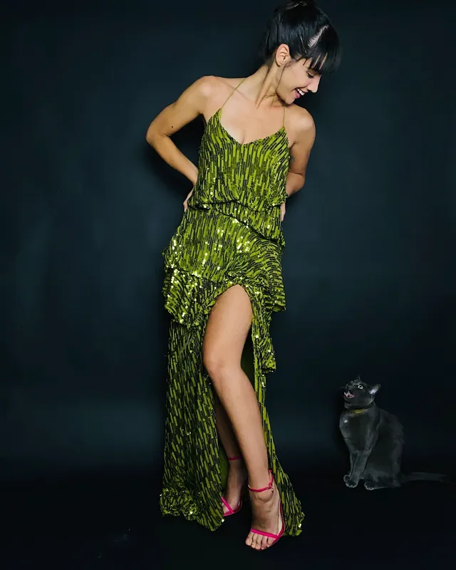 María Gabriela de Faría posing in a green dress and pink heels.
