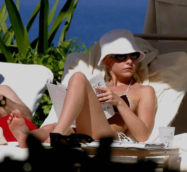 Sarah Michelle Gellar reclining on a sunlounger in a hat with a bare sole visible.