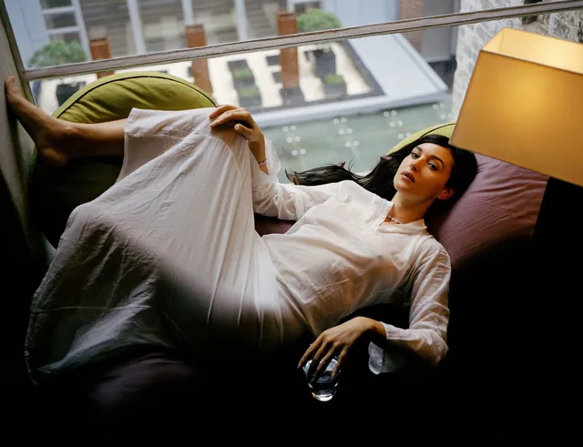 Monica Bellucci reclining on a sofa in a flowing white outfit.
