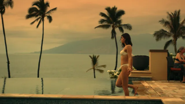 Alexandra Daddario standing barefoot beside a pool at sunset.