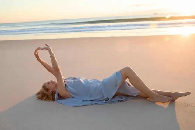 Teresa Palmer reclining on a beach at sunset.