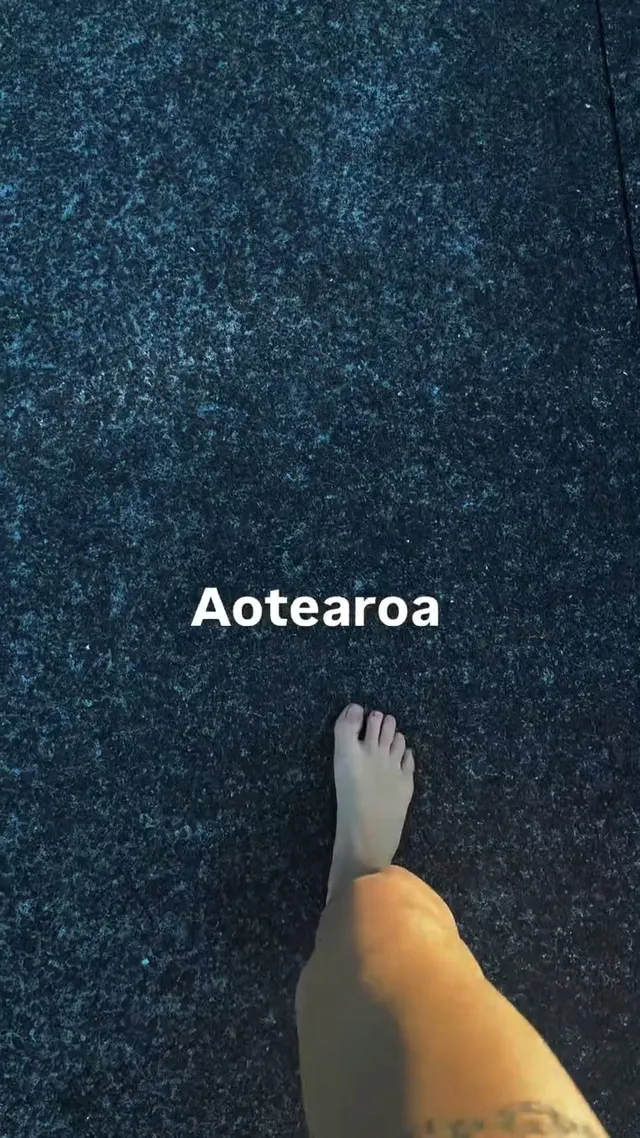 Tove Lo walking barefoot across dark carpet.