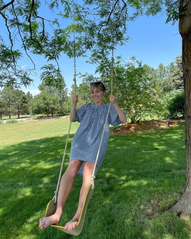 AnnaSophia Robb sitting on a garden swing in a pale dress.