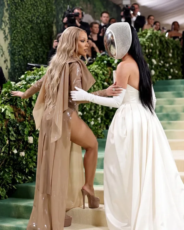 Doja Cat standing beside another person at an event in tan platform heels.
