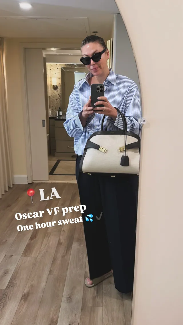 Maria Sharapova taking a mirror photograph in heels and dark trousers.