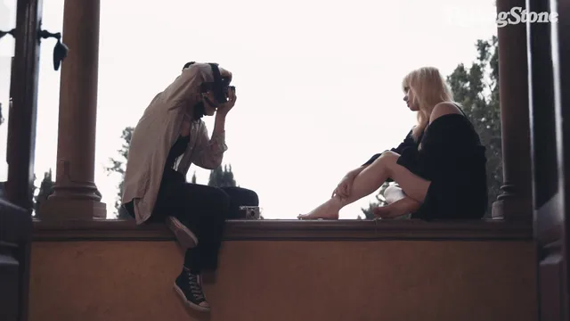 Billie Eilish a barefoot interview beside a window.