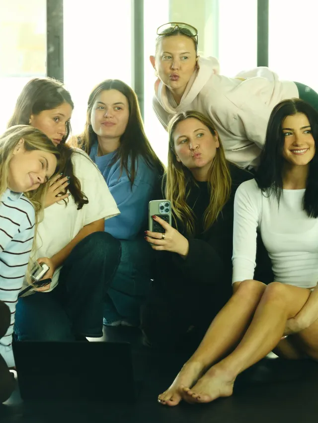 Charli D’Amelio sitting barefoot with a group on a sofa.