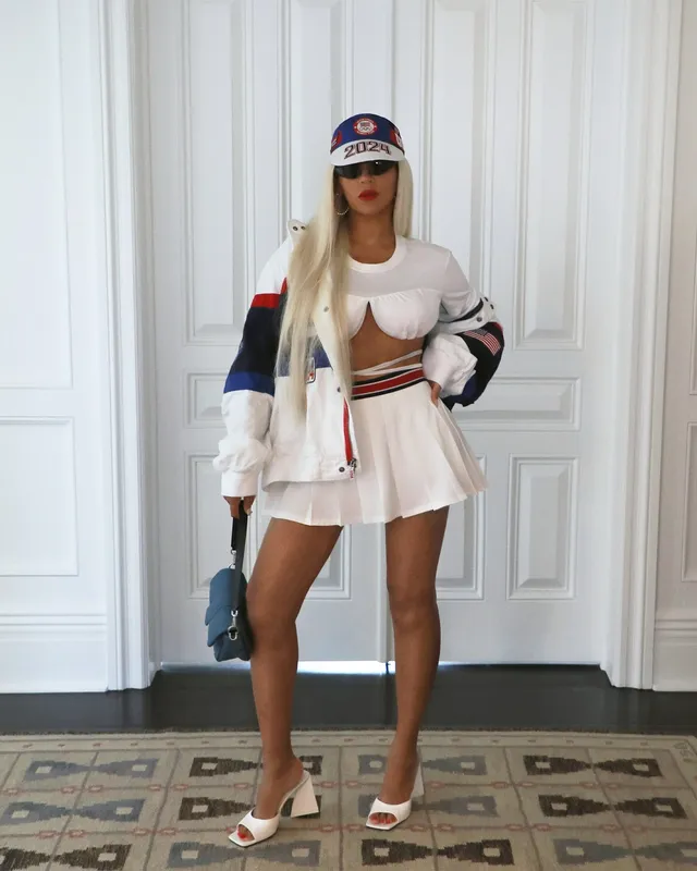 Beyoncé posing in a white sporty outfit and open-toe heels.