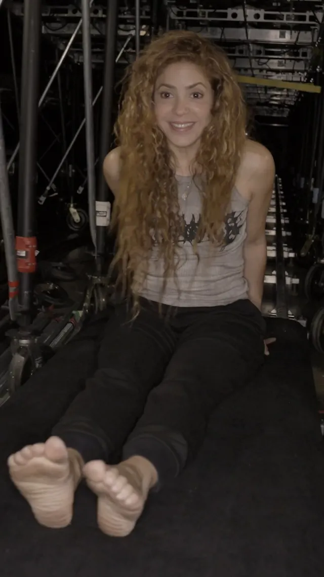 Shakira a seated backstage photograph with socks and bare toes.