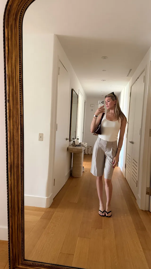 Eugenie Bouchard taking a mirror photograph in black flat sandals and a pale outfit.