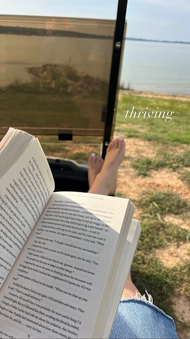 Brec Bassinger reclining barefoot by a window while reading.