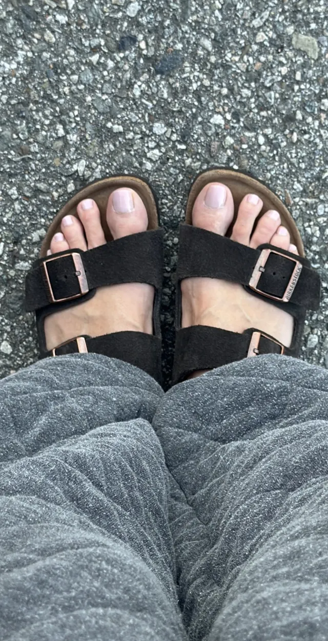 Heidi Klum wearing black buckled flat sandals with jeans.