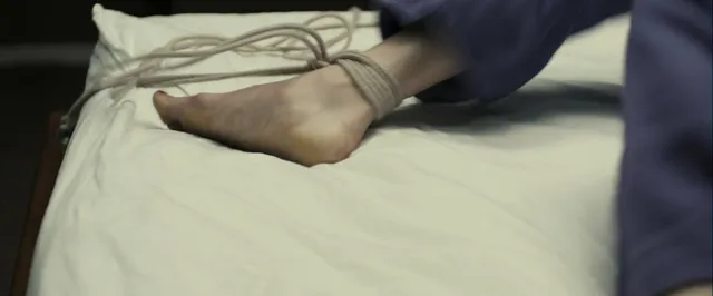 Gemma Arterton resting a bound ankle on a bed in a screen scene.