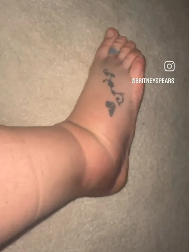 Britney Spears a close detail of a bare foot with an ankle tattoo.
