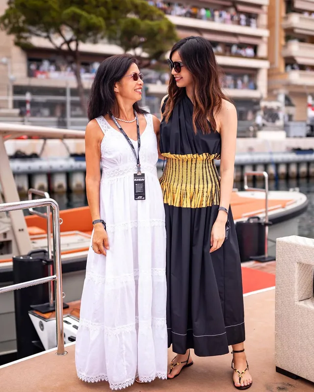 Gemma Chan standing with a guest on a boat deck in flat sandals.