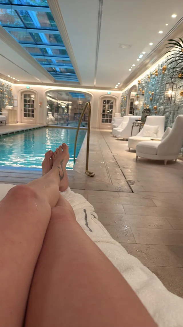 Adriana Lima relaxing barefoot beside an indoor pool.