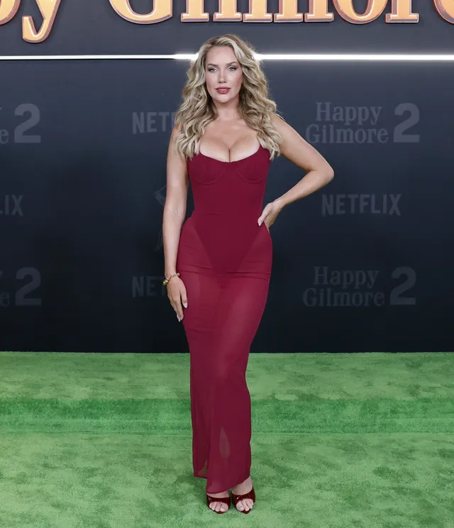 Paige Spiranac wearing black heeled sandals and a burgundy gown at a film event.