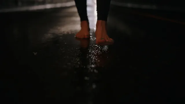 Peyton List standing barefoot on a reflective floor.