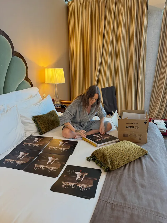 Tove Lo sitting barefoot on a bed beside printed photographs.