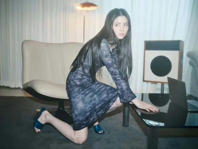 Han So-hee posing beside a table in a patterned dress and heels.