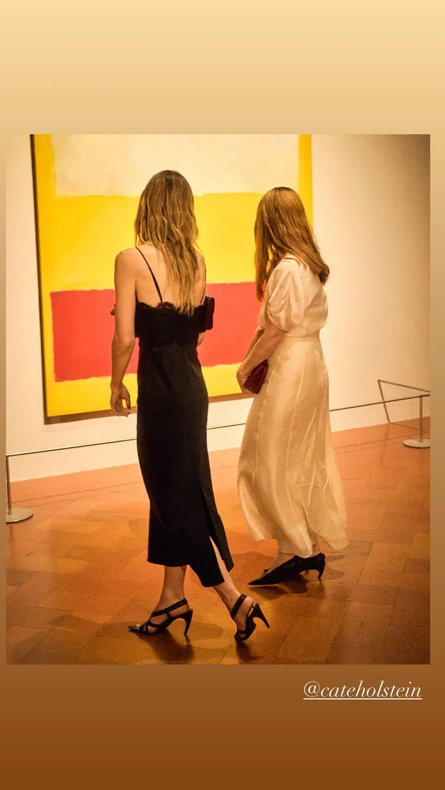 Olivia Wilde standing beside another person in a black dress and heels.