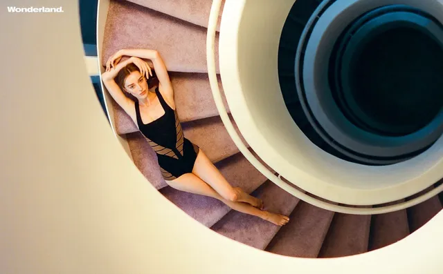 Phoebe Dynevor reclining in a sculptural circular setting in a studio.