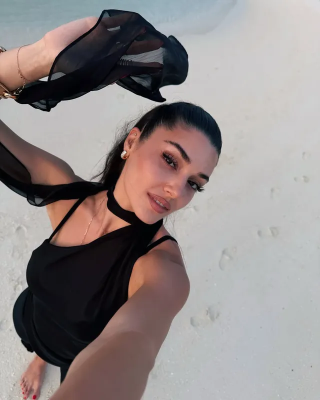 Hande Erçel taking a mirror photograph in a black outfit.