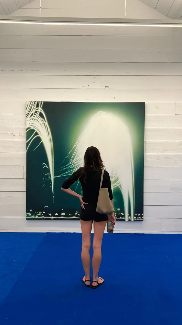 Phoebe Tonkin standing before a painting in a short dark outfit.