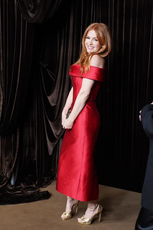 Isla Fisher posing for an event portrait in a red dress.