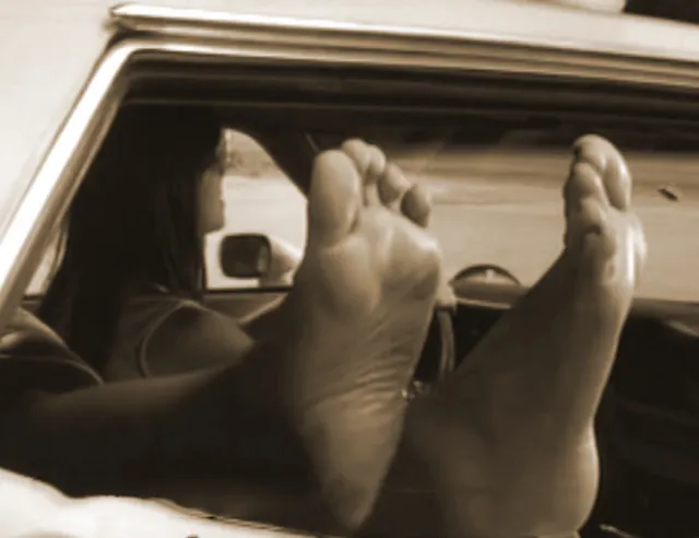 Rosario Dawson resting bare feet through a car window.