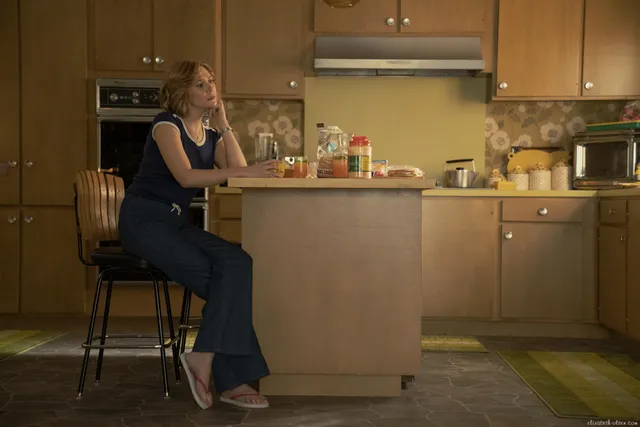 Elizabeth Olsen sitting at a kitchen counter in pointed heels.
