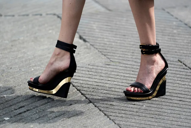 Eva Green walking in black wedge sandals on a pavement.