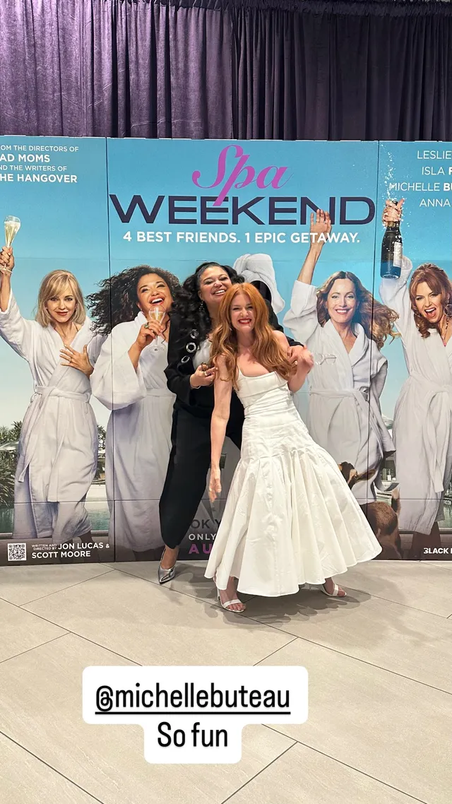 Isla Fisher posing with companions beside a film poster.