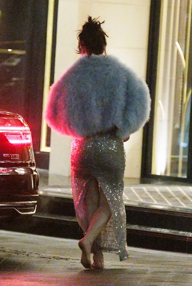 Lily James walking barefoot beside a car wearing a shimmering skirt.