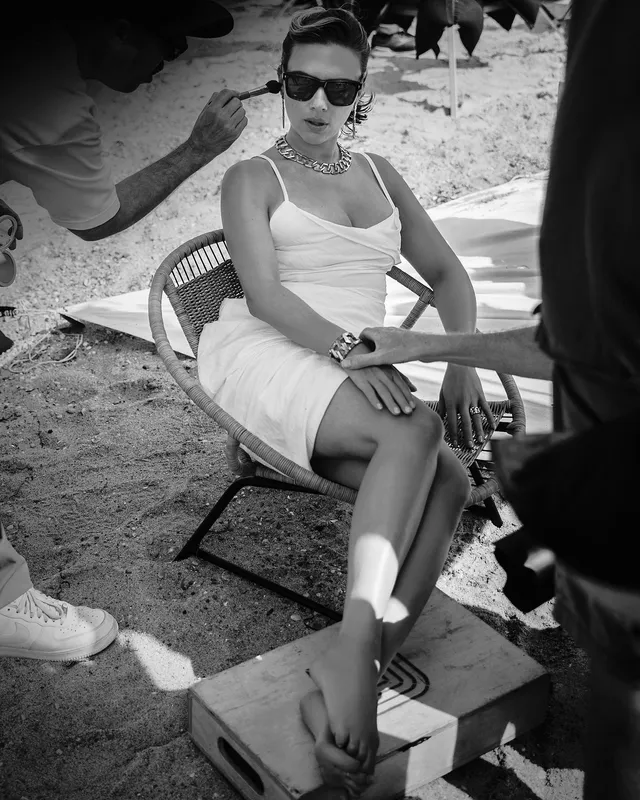 Scarlett Johansson: seated outdoors while being photographed in a black-and-white portrait.