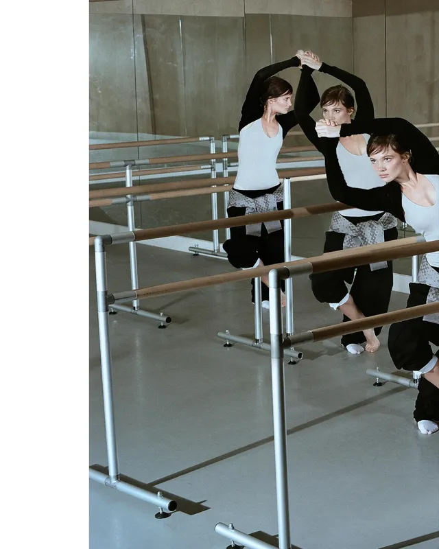 Freya Allan practising at a ballet barre in dance clothes and a white sock.