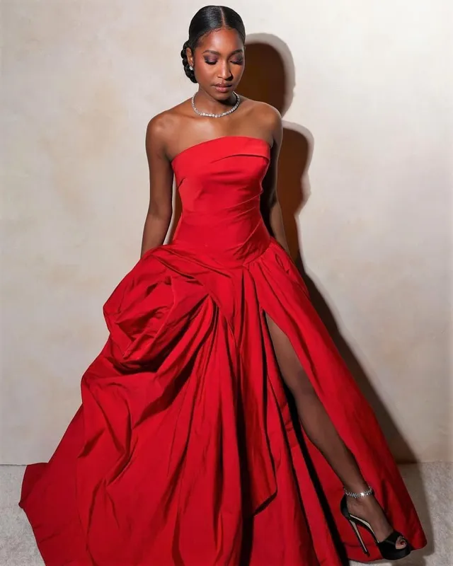 Carlacia Grant sitting in a red gown with a black heel visible.