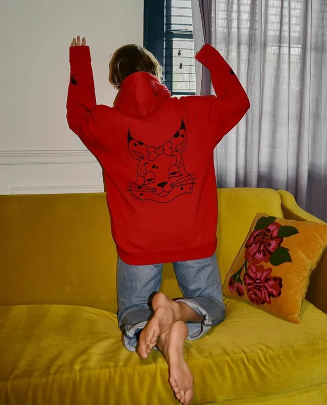 Tove Lo kneeling on a yellow sofa with bare soles visible.