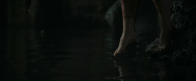 Kathryn Newton stepping barefoot beside a pool in a film scene.