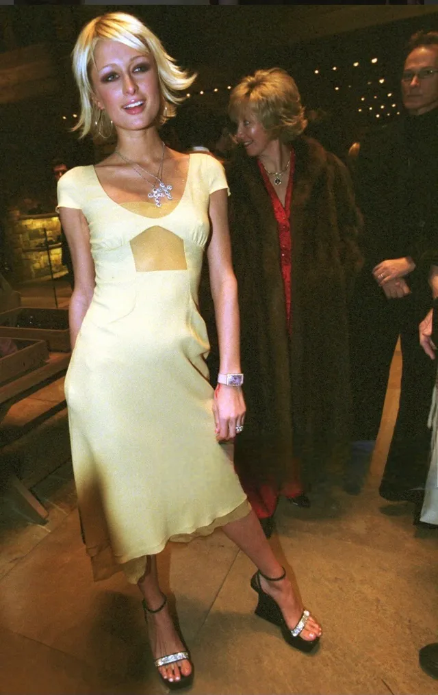 Paris Hilton wearing a pale dress and sandals at an event.
