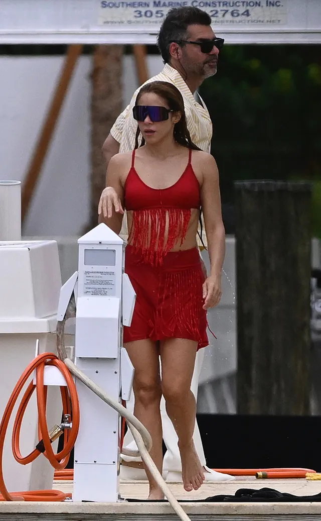 Shakira a red outfit while walking along a dock.