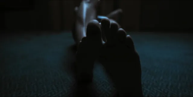 Alice Eve lying on a floor with her feet toward the camera in a scene.