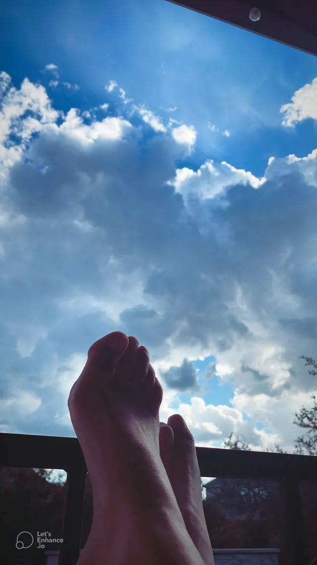 Melissa Barrera raising bare feet against a bright sky.