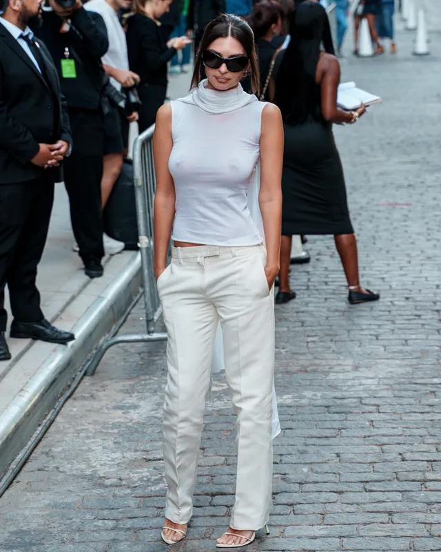 Emily Ratajkowski walking in a pale outfit and metallic heels.