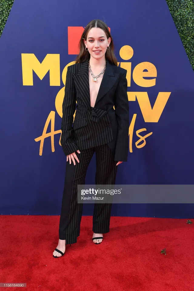 Victoria Pedretti posing at a movie awards event in a dark suit.