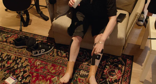 Billie Eilish a seated photograph with taped ankles.