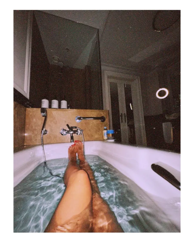 María Gabriela de Faría reclining barefoot in a bathtub.