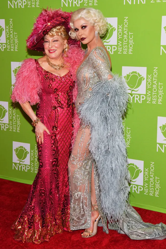 Catherine Zeta-Jones posing at an event beside a companion in a silver gown.